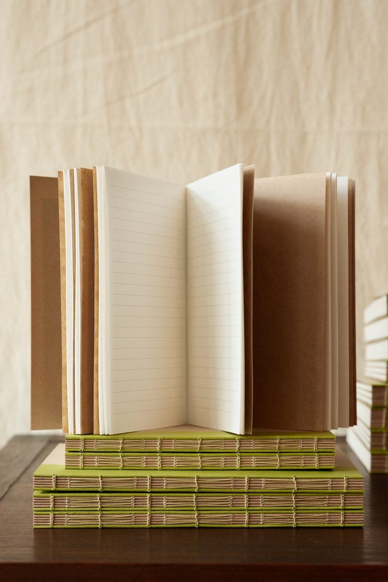 Carnets à couture apparente, l'un ouvert sur une page lignée