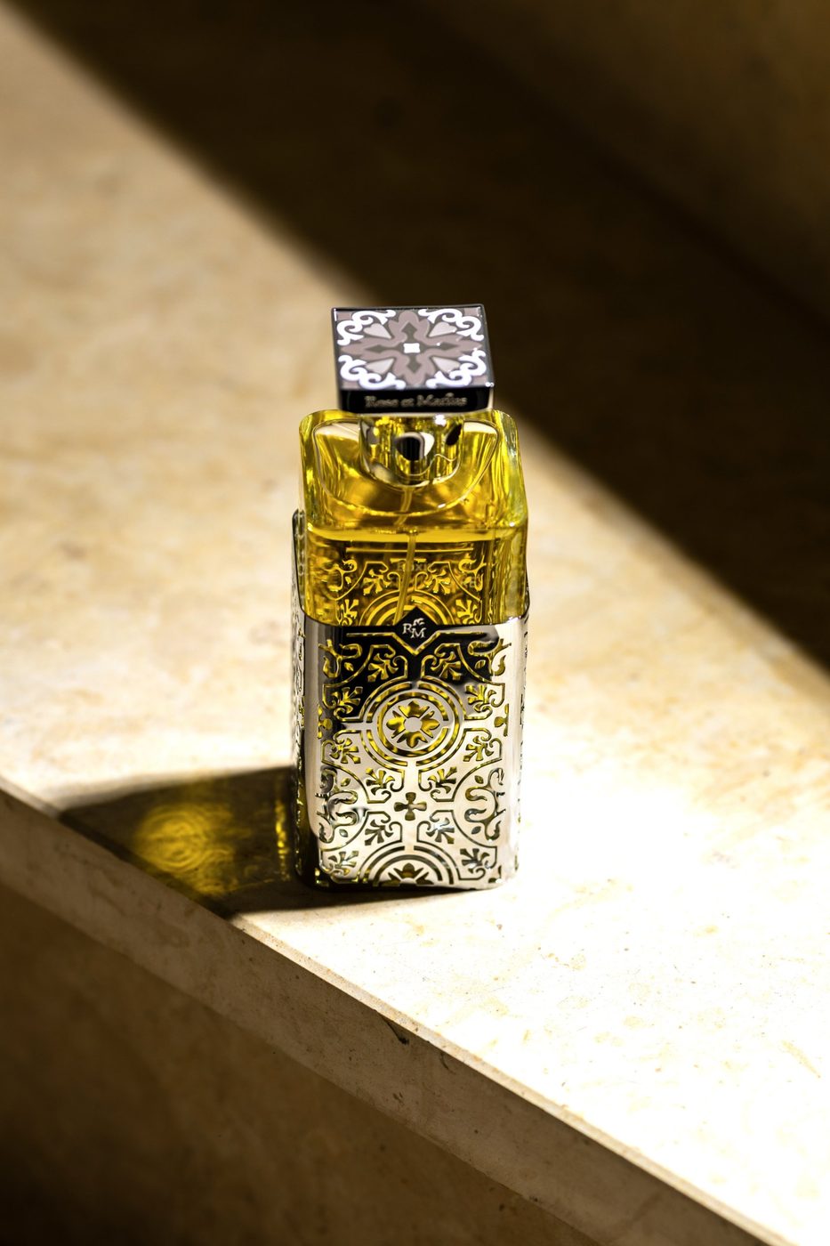 Flacon de parfum Rose et Marius à l'habillage ciselé, dans un rayon de soleil